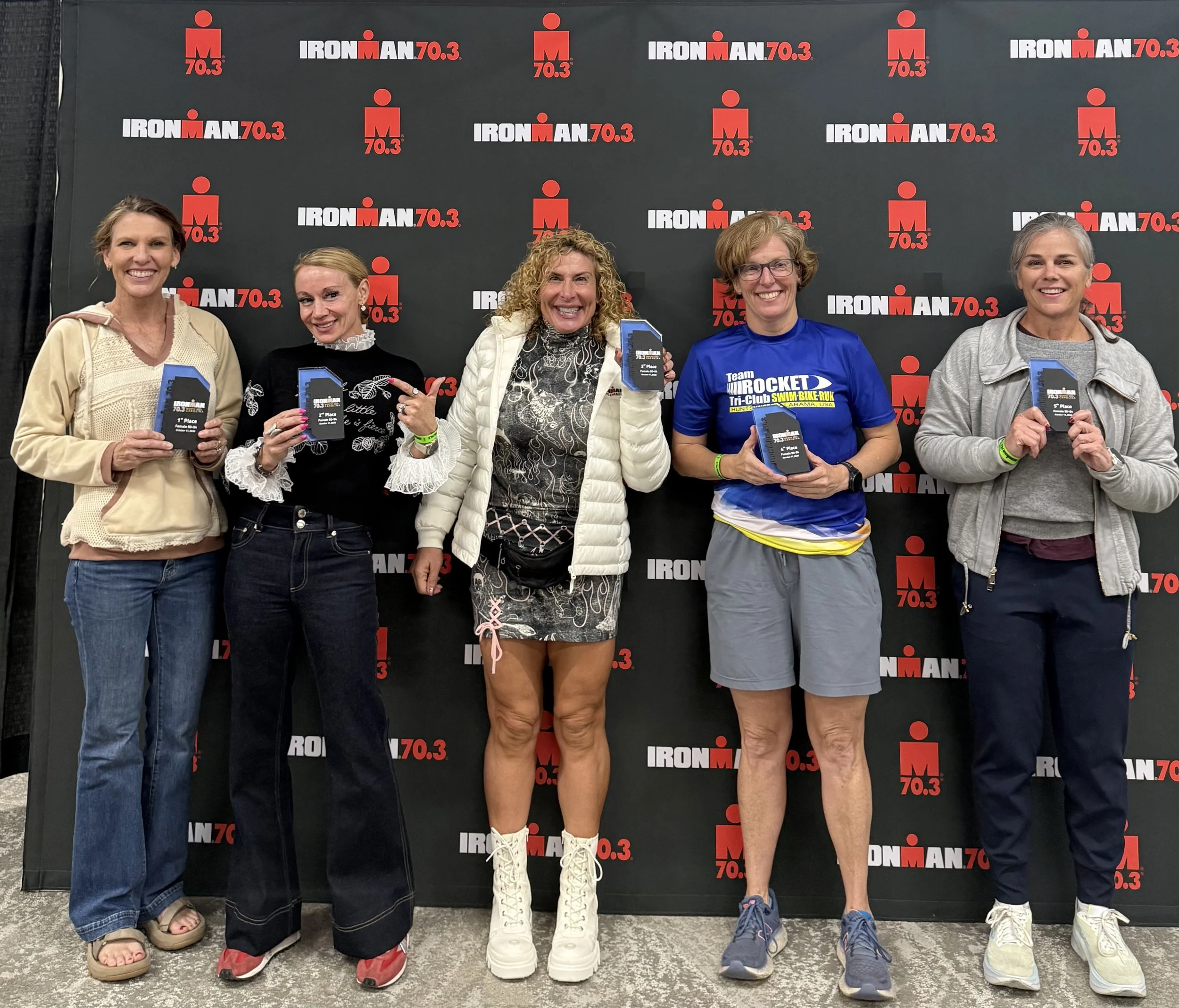 Rosa Laura celebrating third place in the women's 50–54 age group with fellow podium finishers at IRONMAN 70.3 North Carolina 2026.