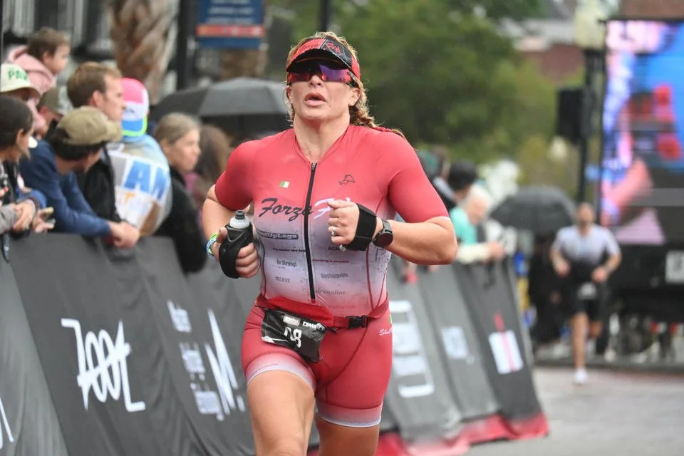 ForzaFit coach Rosa Laura running toward the finish line in rainy Wilmington at IRONMAN 70.3 North Carolina 2026.
