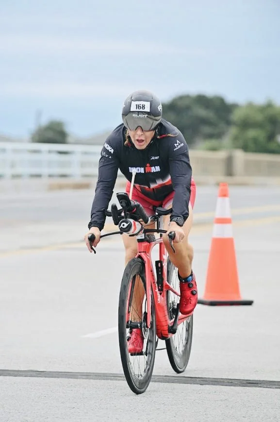 ForzaFit coach Rosa Laura riding her triathlon bike on a bridge during IRONMAN 70.3 North Carolina 2026.