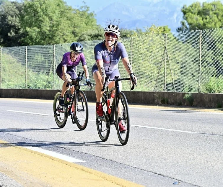 Rosa Laura Saggese Elbooz smiling and sticking out her tongue while riding Black Forza on the bike course at the 2026 IRONMAN 70.3 World Championship in Nice, France.