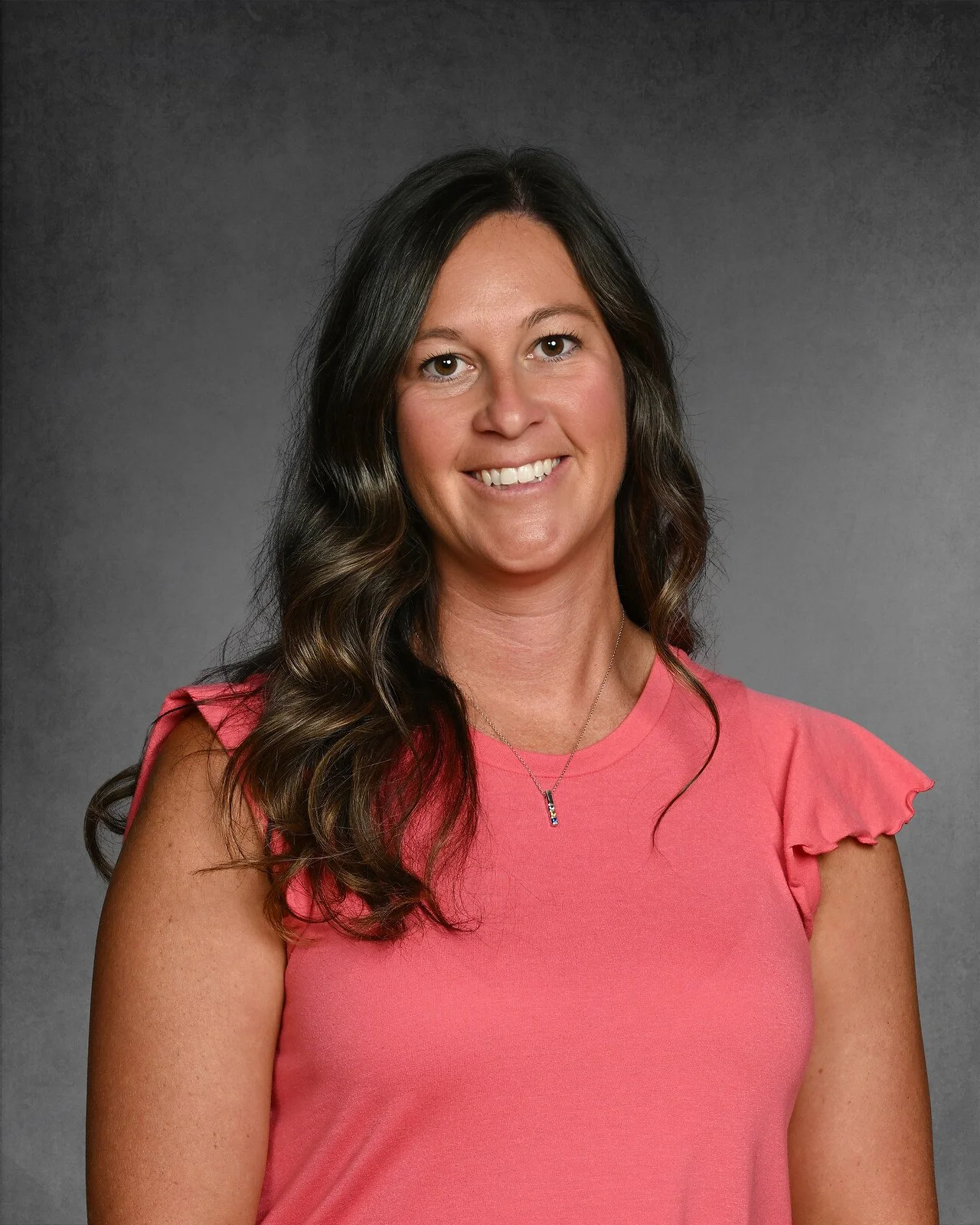 Woman smiling in floral blouse against gray background