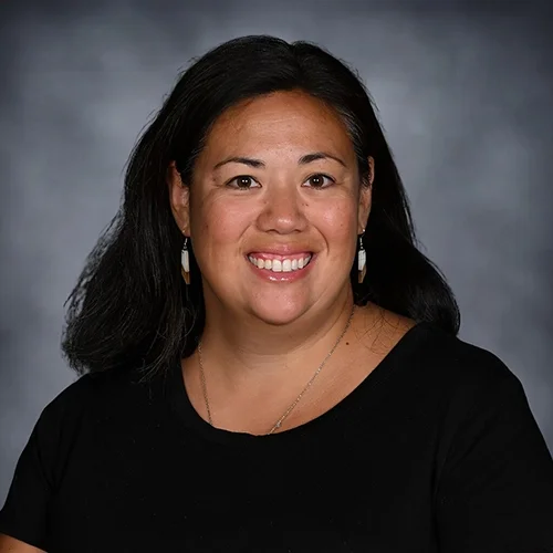 Portrait of a smiling woman with short black hair wearing a green top.