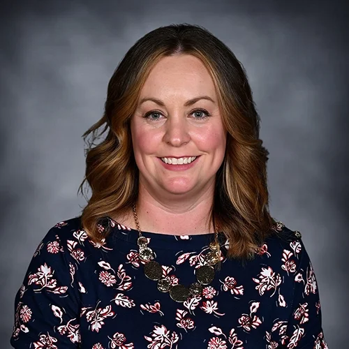 Portrait of an older woman with short hair, wearing glasses and a red shirt.