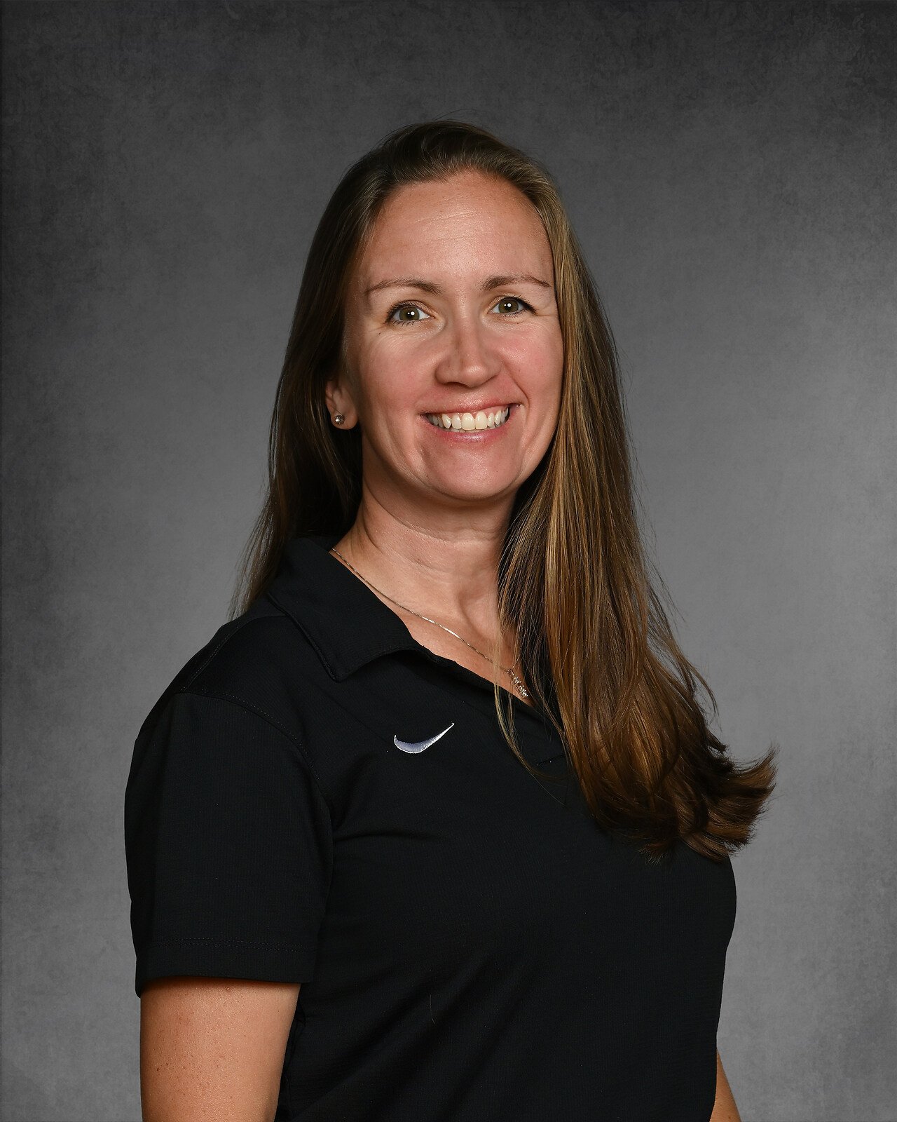 Woman with long hair wearing a maroon polo shirt with "Eagles" logo, smiling against a gray background.