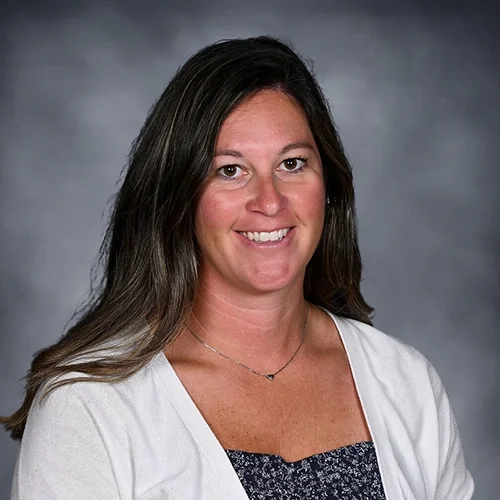 Woman smiling in floral blouse against gray background