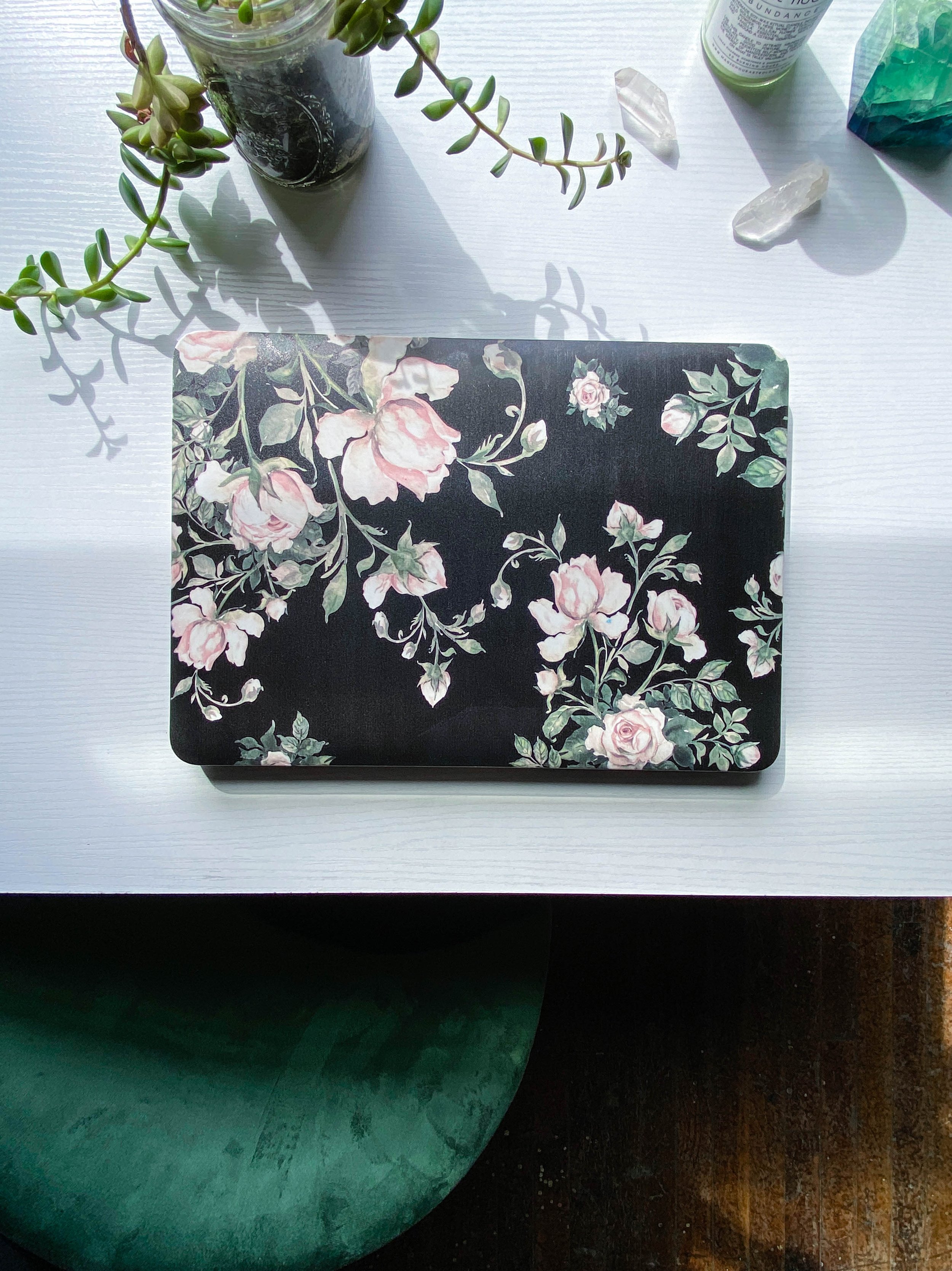  white desk with a black floral laptop and plants 