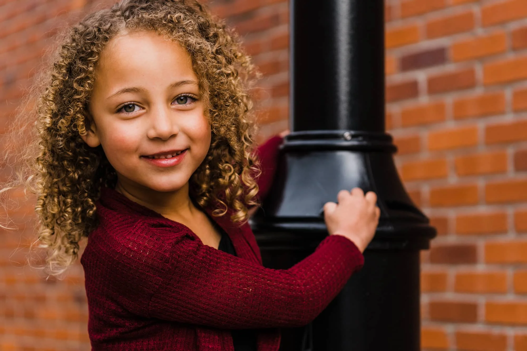 Portrait of young woman hanging from a lamp post.