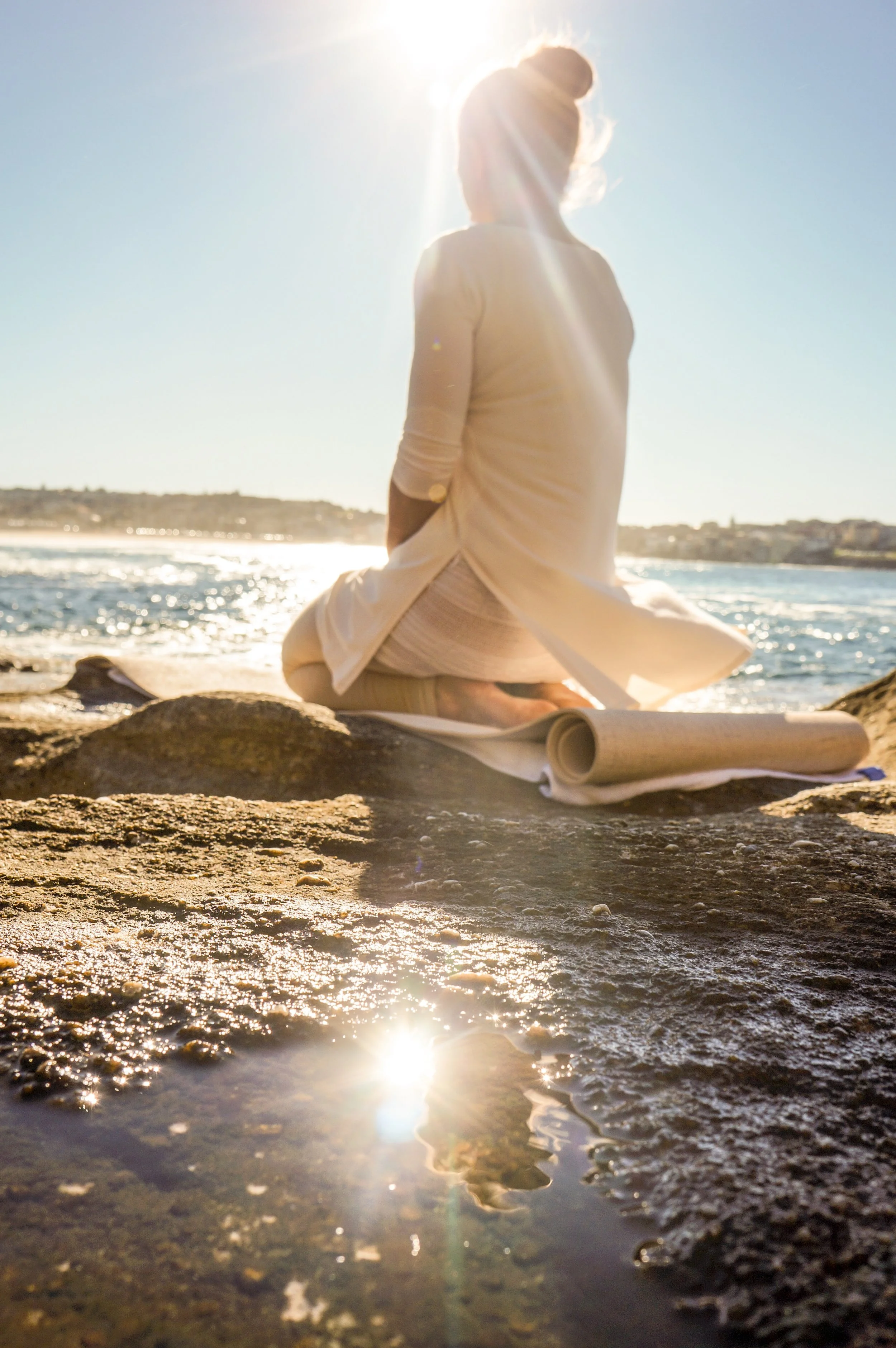 Woman practising yoga on a LovEarth travel mat beside the Australian coastline.