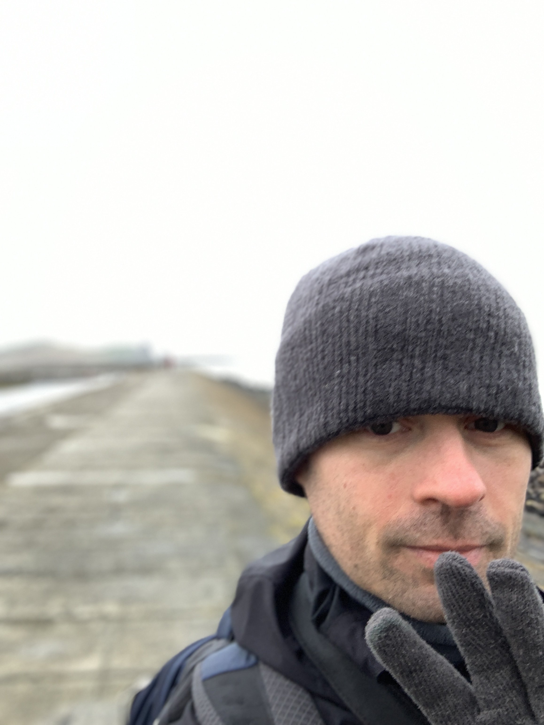 White man in grey beanie hat and coat.