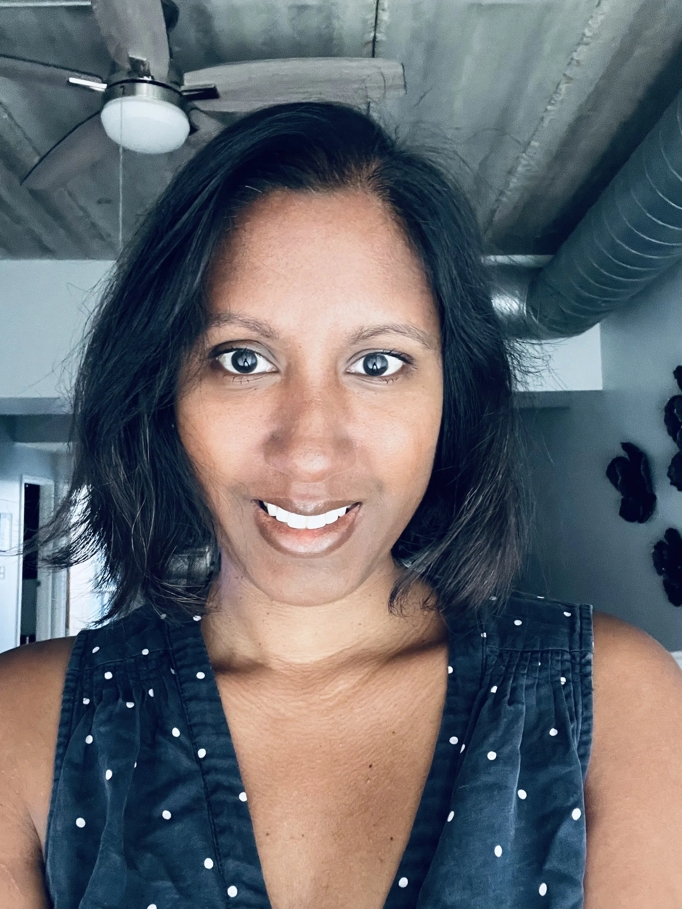 Brown woman with short straight dark hair, smiling to camera.