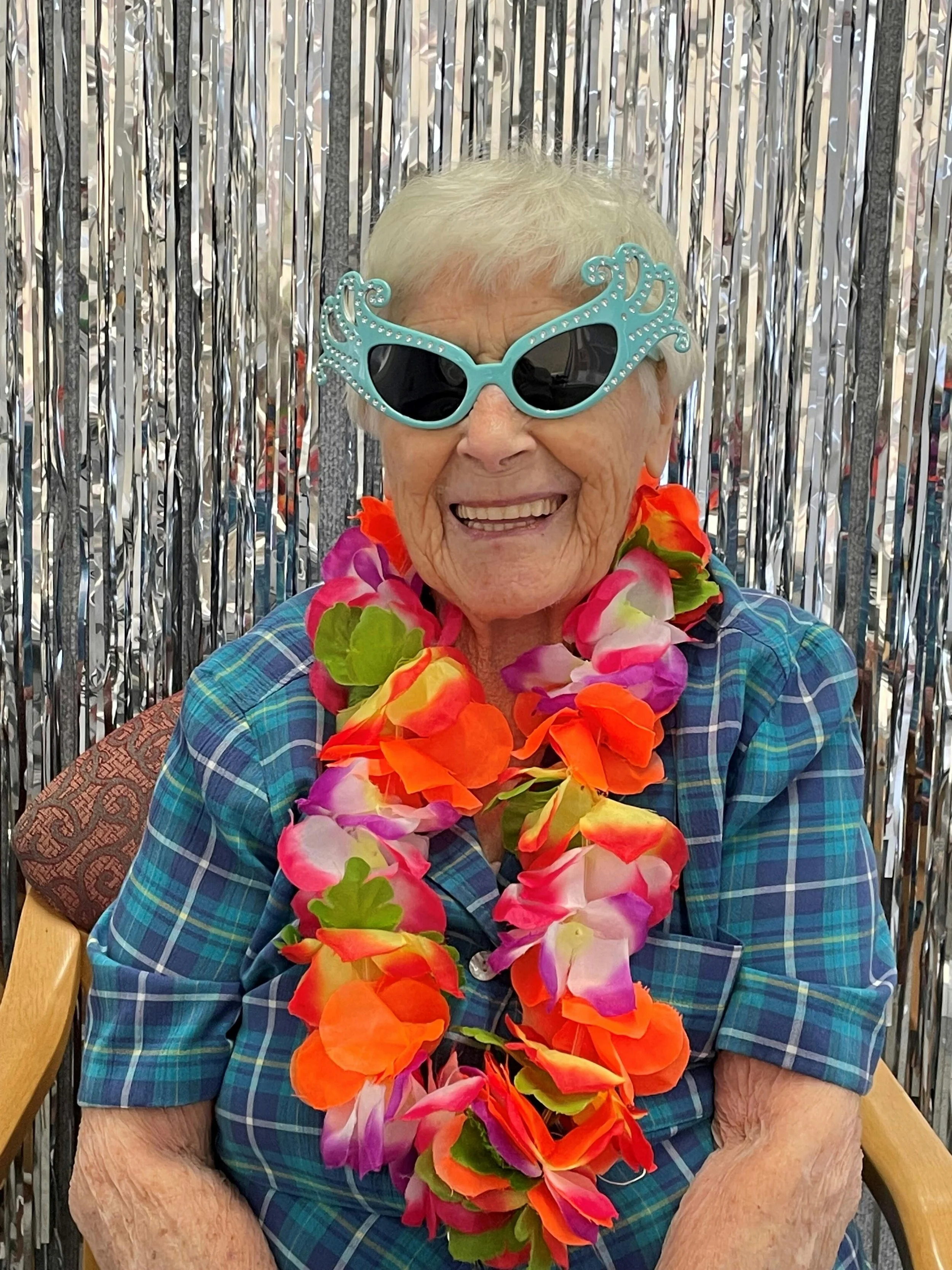 Elderly woman wearing snazzy sunglasses and a colored lei