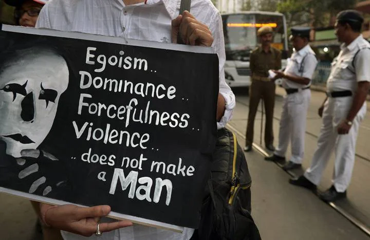 An Indian social activist holds a placard as policemen (background R) look on during a rally on the International Day for the Elimination of Violence against Women in Kolkata on November 25, 2013. Getty Images.