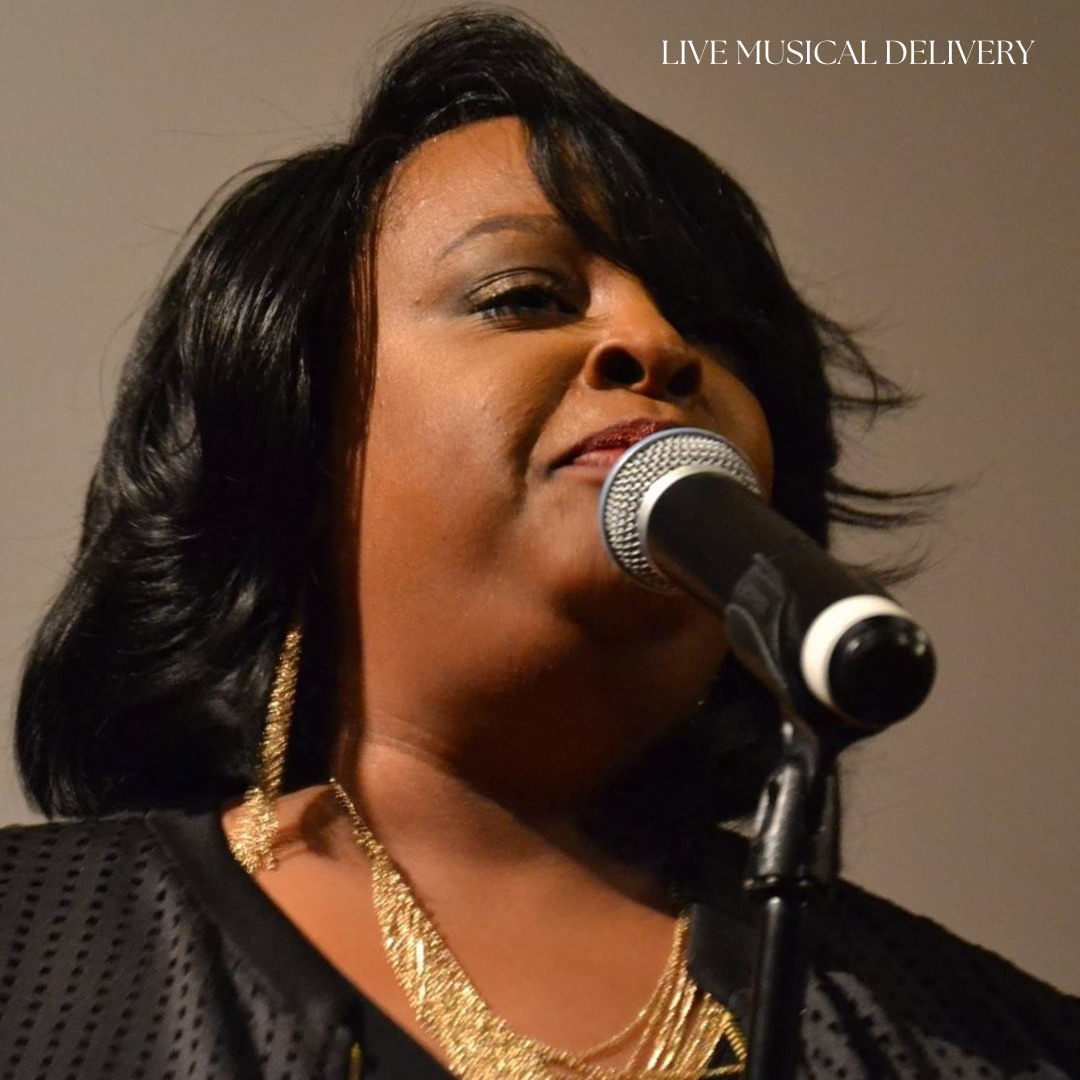 A woman singing into a microphone during a live musical performance, wearing gold jewelry and a black outfit. The text in the top right corner says 'LIVE MUSICAL DELIVERY'.