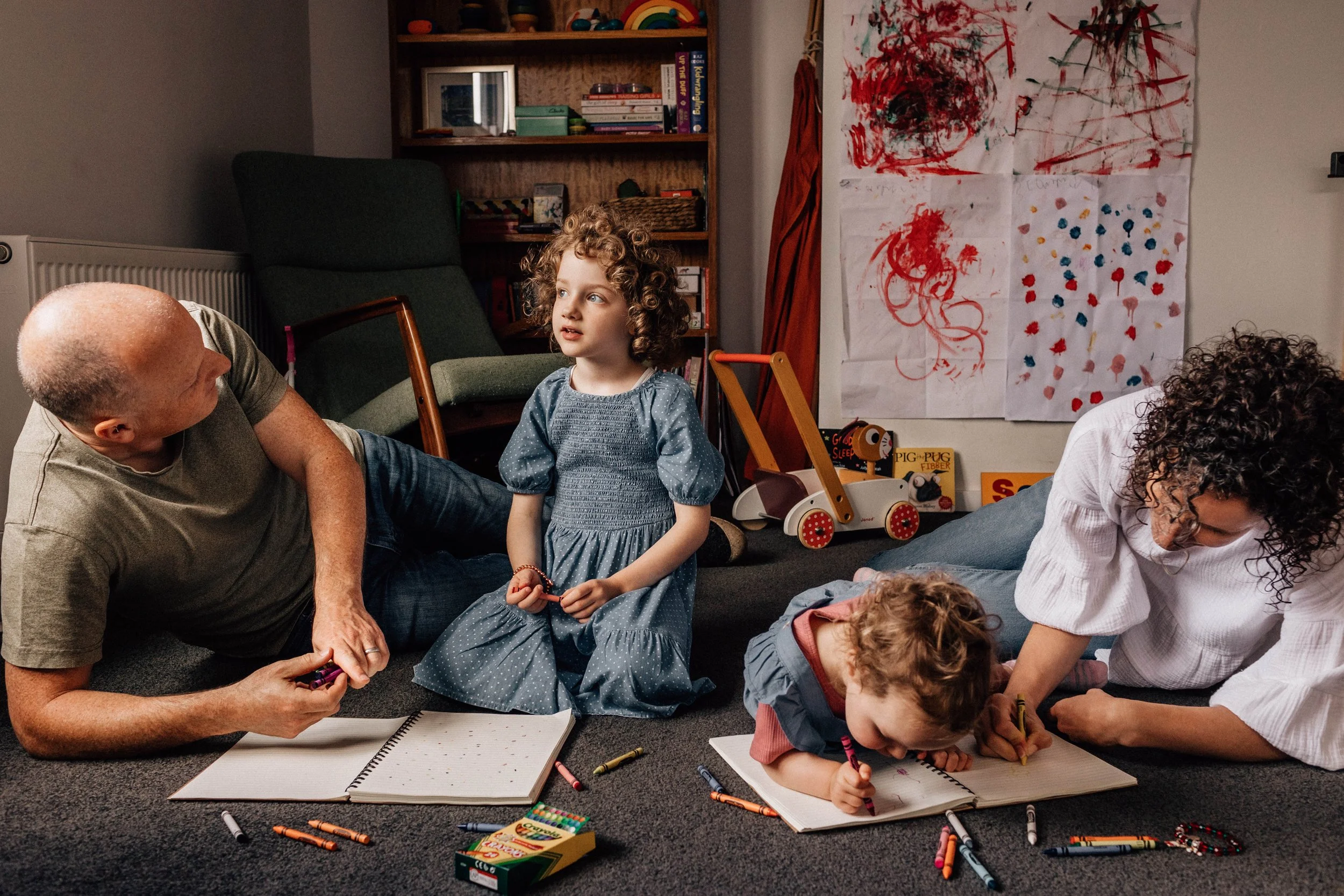 family of four lying on living room floor colouring with crayons