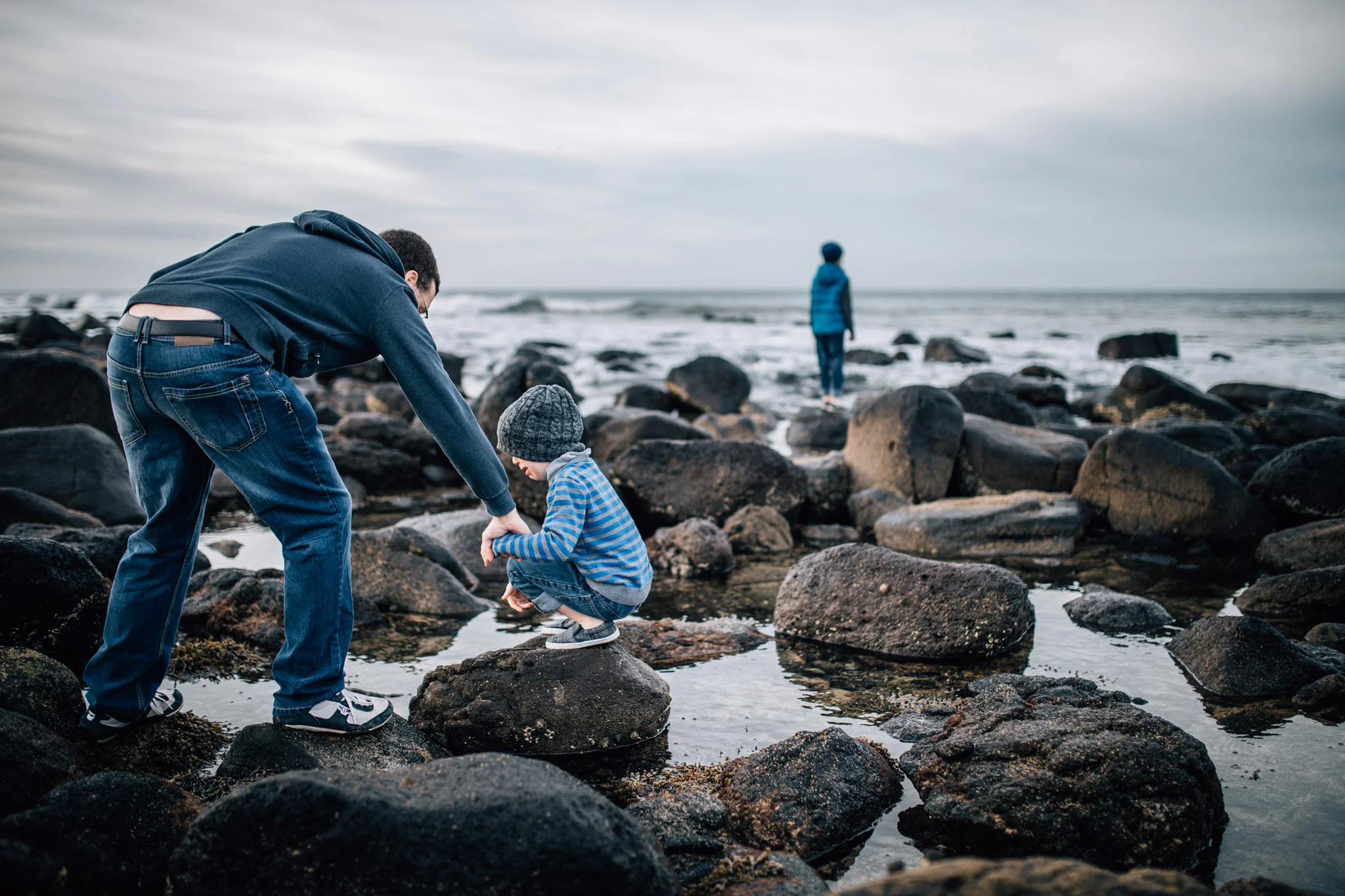 father comforting son on rocks at beach (1 of 1).jpg