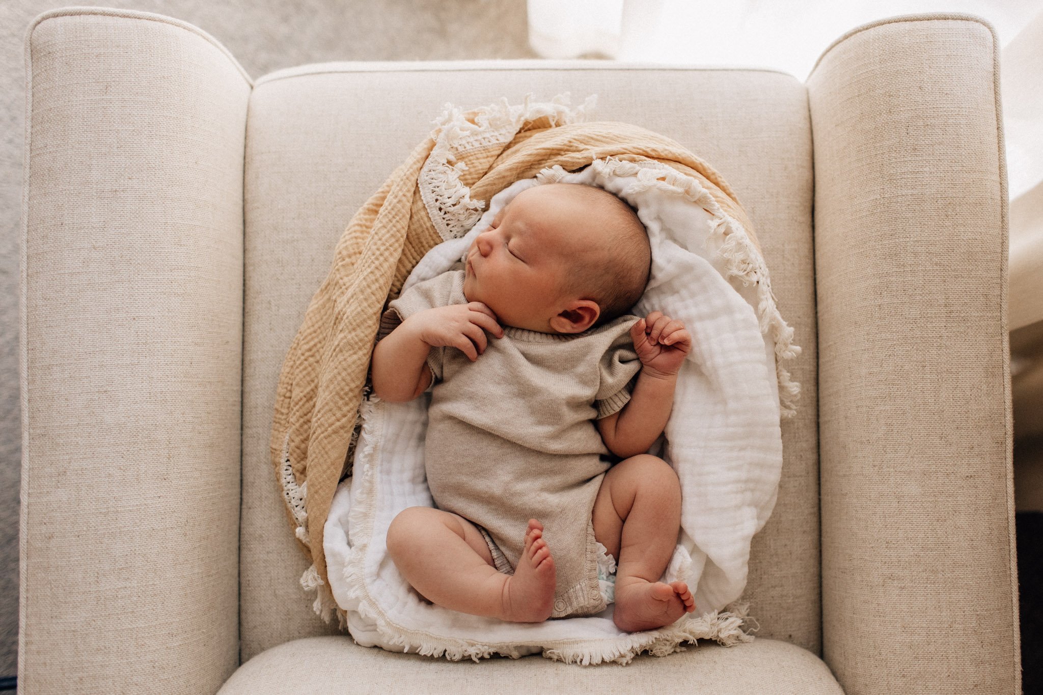 Newborn baby in blanket nest on white chair.jpg