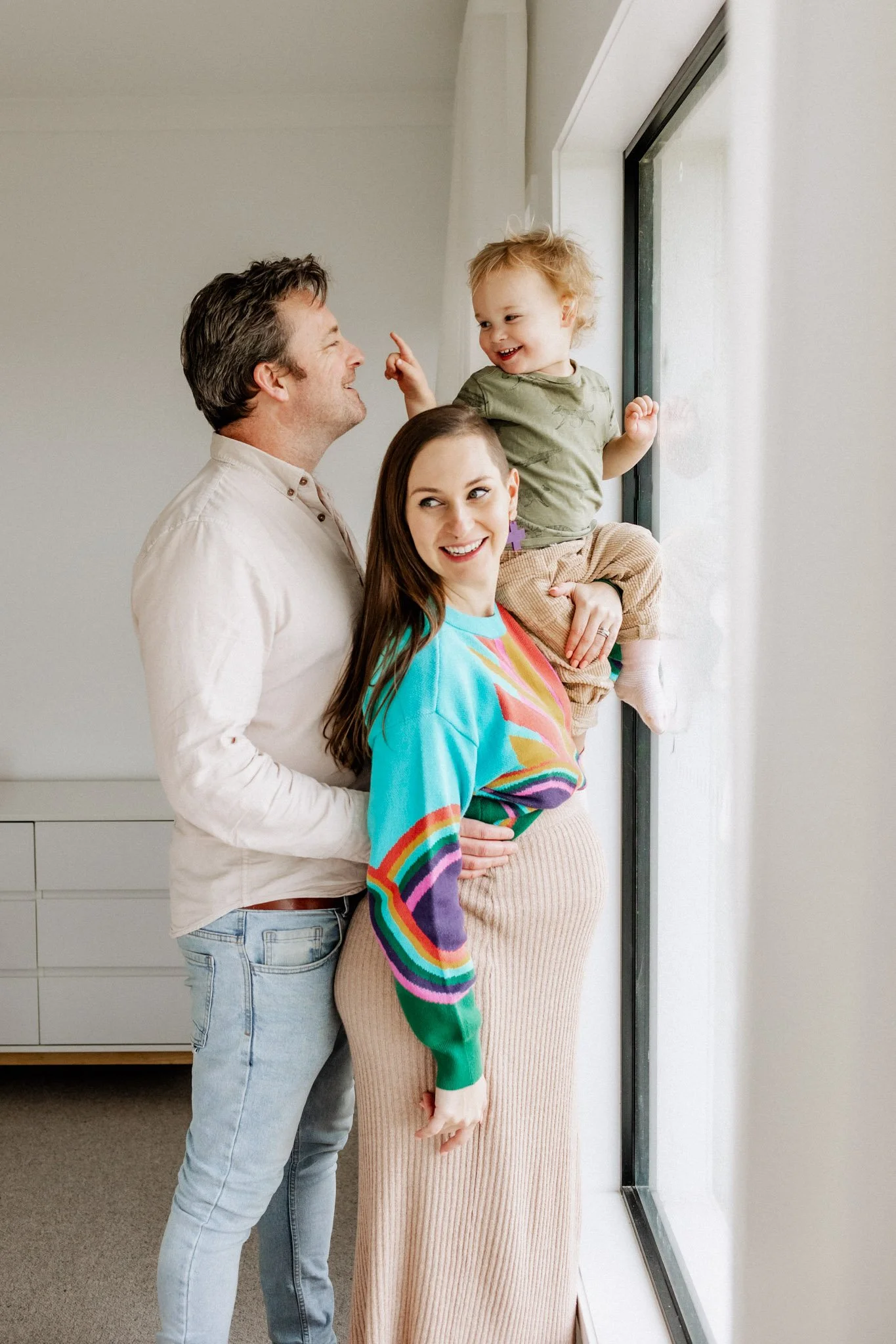 pregnant mother with husband and toddler son at bedroom window