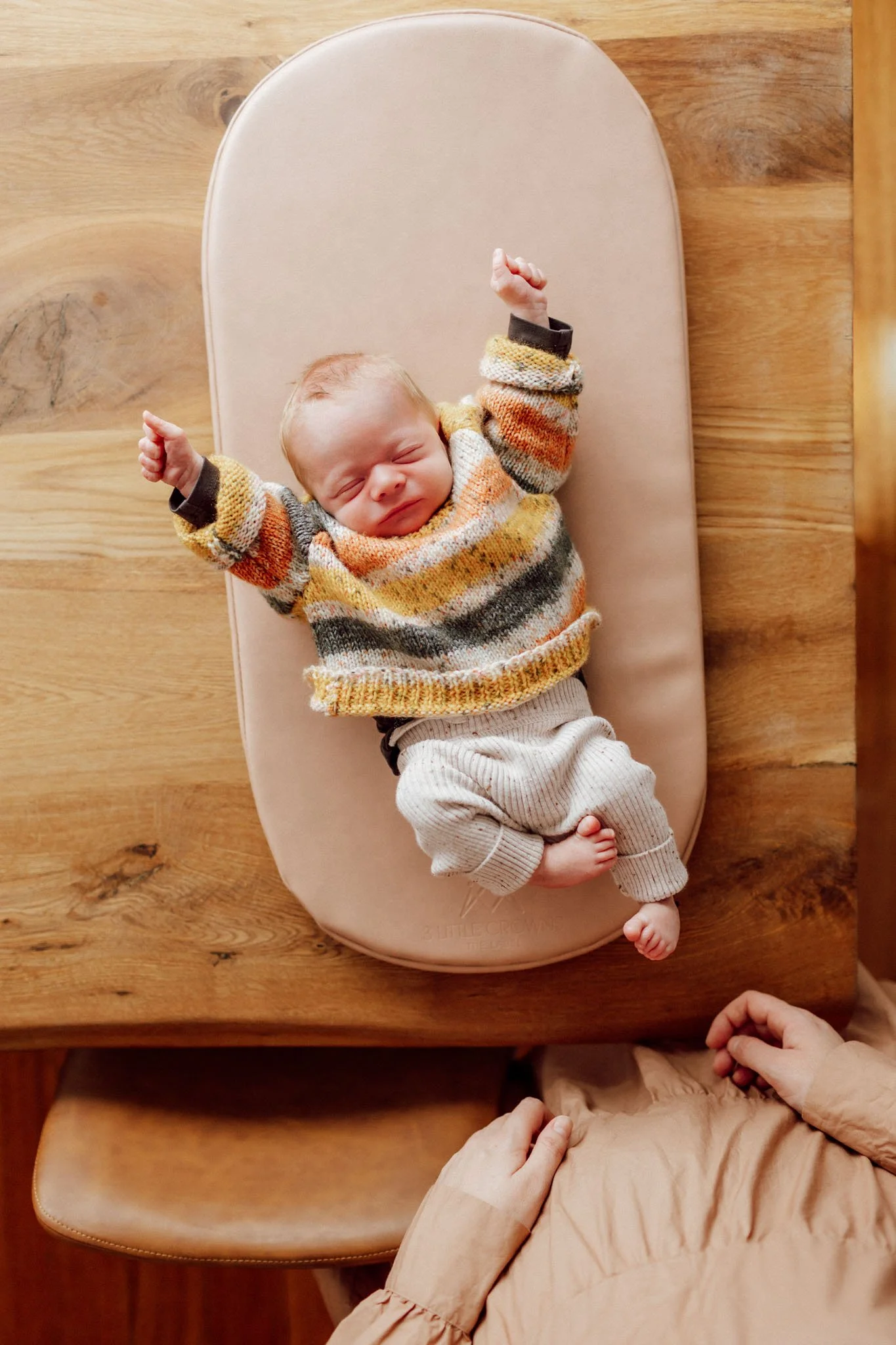 baby on change table in stretching in sweater