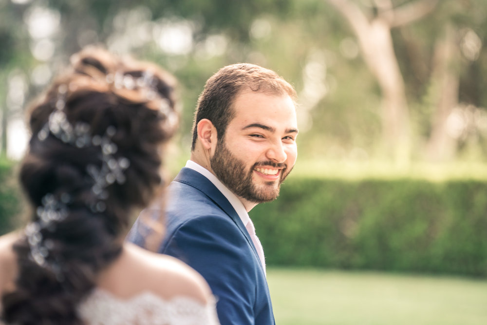 Portrait of the groom turning and smiling  to see his bride during the first book on their wedding day in Brea California