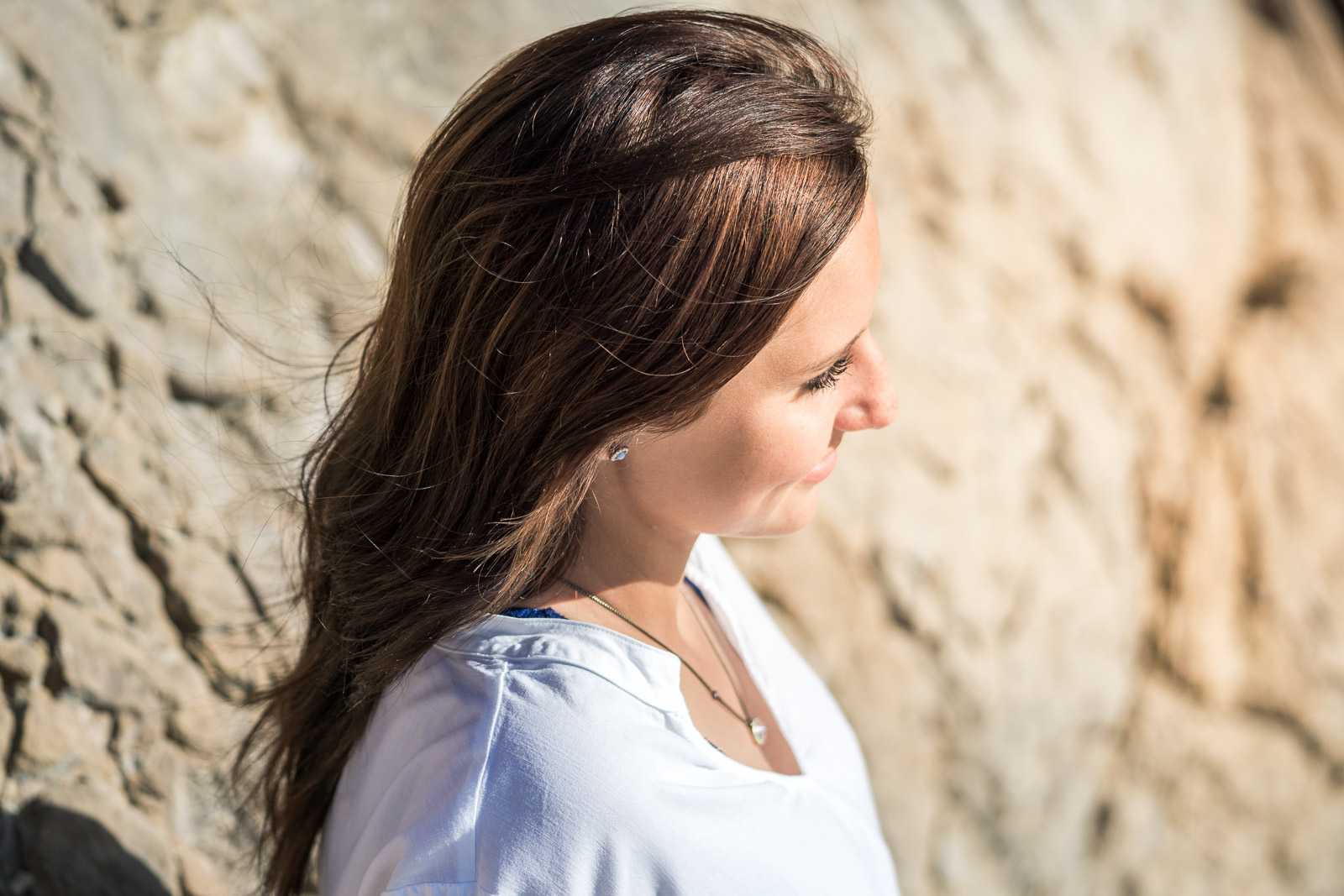 Graduation portrait of a female student posing Against The seawall at Corona Del mar state beach