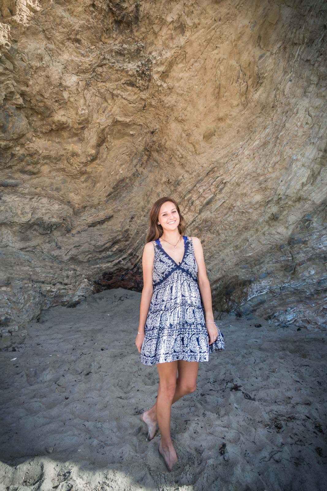 Graduation portrait of a female student posing Against The seawall at Corona Del mar state beach