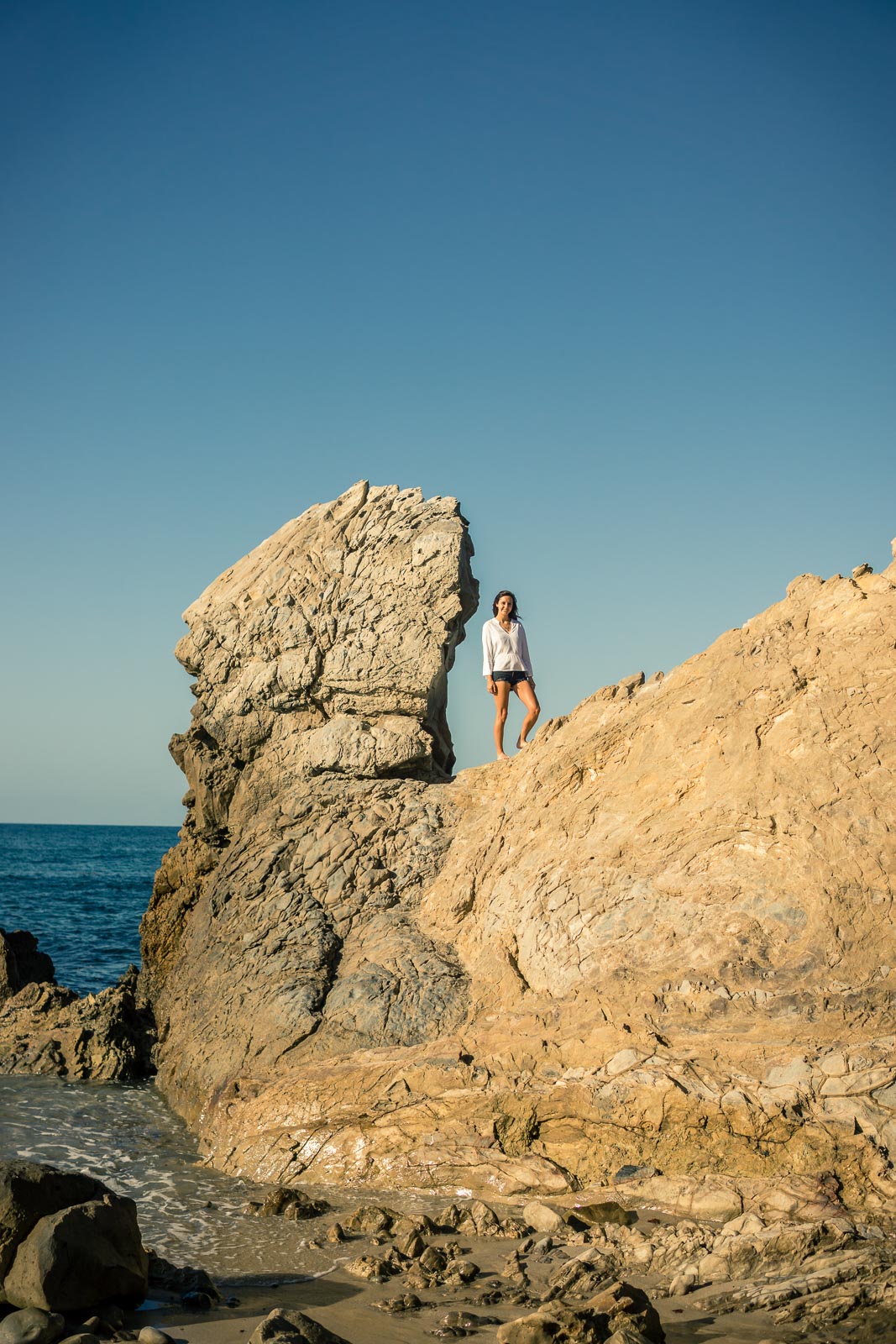 Graduation portrait of a female student posing on the rocks Corona Del mar state beach