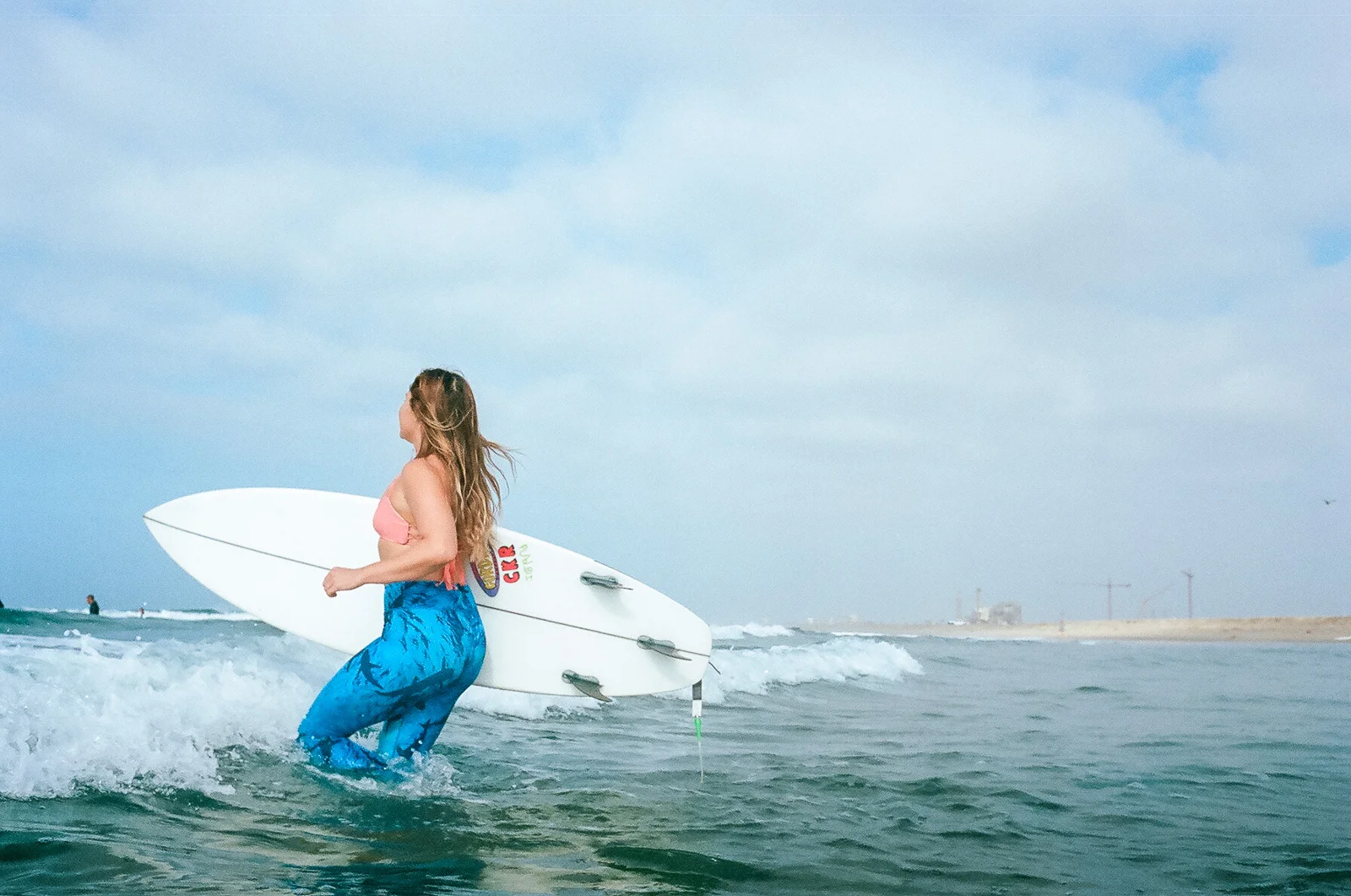 35mm color film Surfing photo shoot at Huntington State Beach with girl surfer jumping into waves for Get wise fool eco-friendly surf company