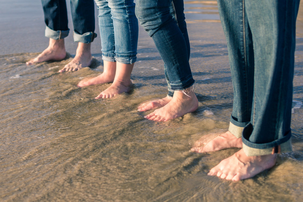  Family portraits of feet in the sandy seashore in blue jeans being backlit during Golden hour at Crystal Cove State Beach in Newport 