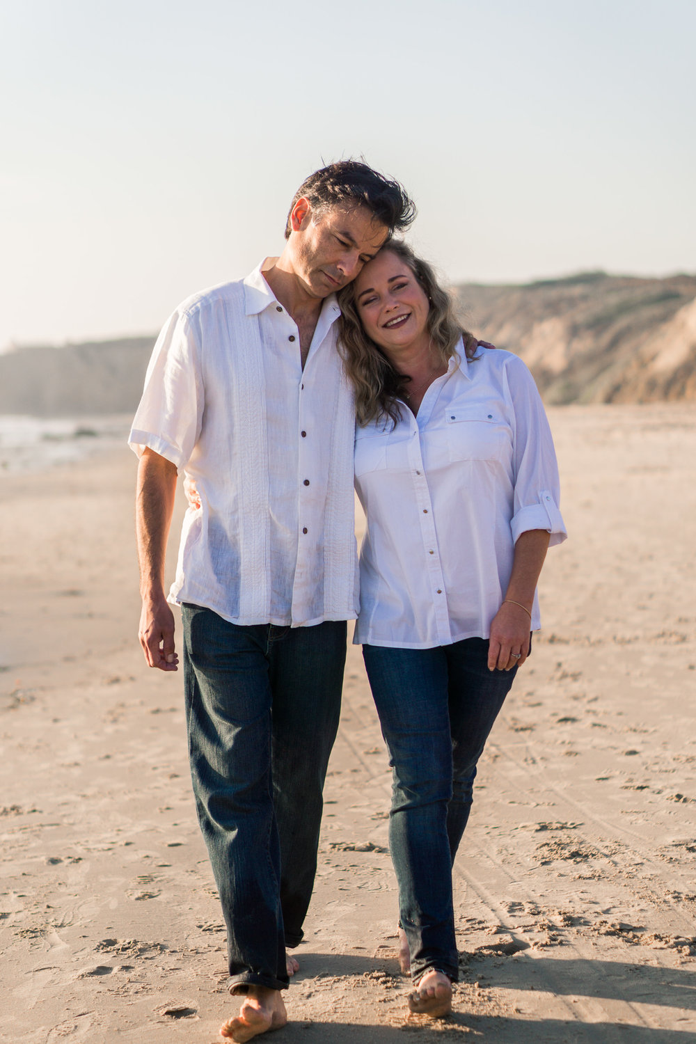 Family portraits of husband and wife walking on the beach holding hands and hugging at Crystal Cove Beach at Crystal Cove Beach in Newport during Golden hour