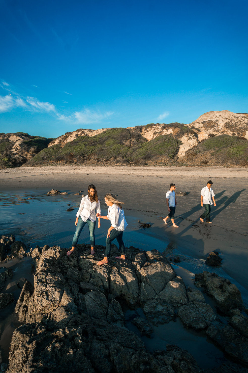 Family portraits of family beach combing on rocks and tidepools during Golden hour at Crystal Cove State Beach in Newport