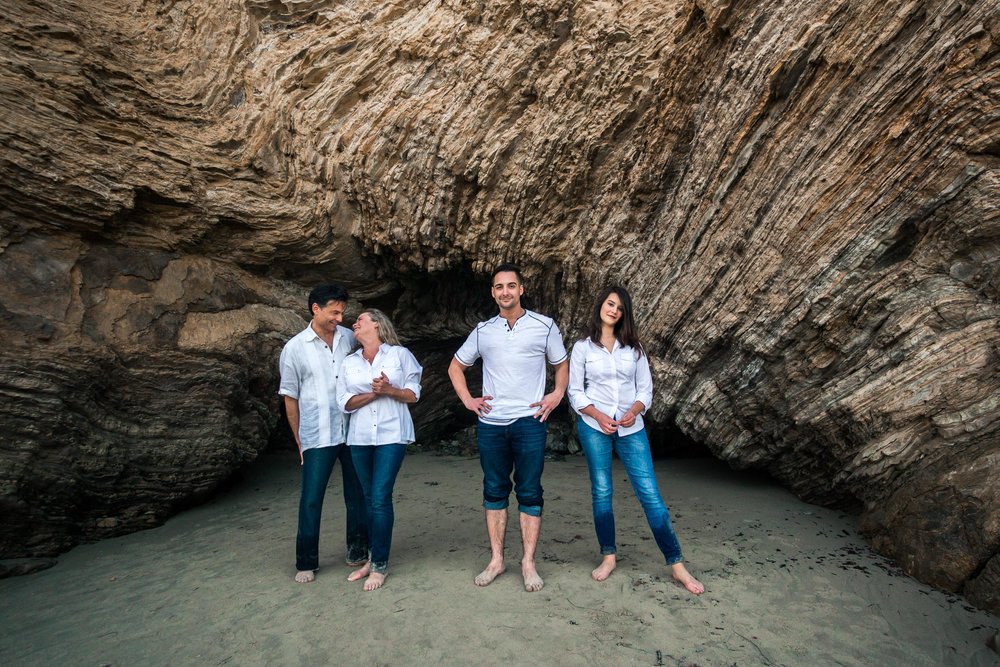 Family portraits of family posing near sea cave and cliff during Golden hour at Crystal Cove State Beach in Newport