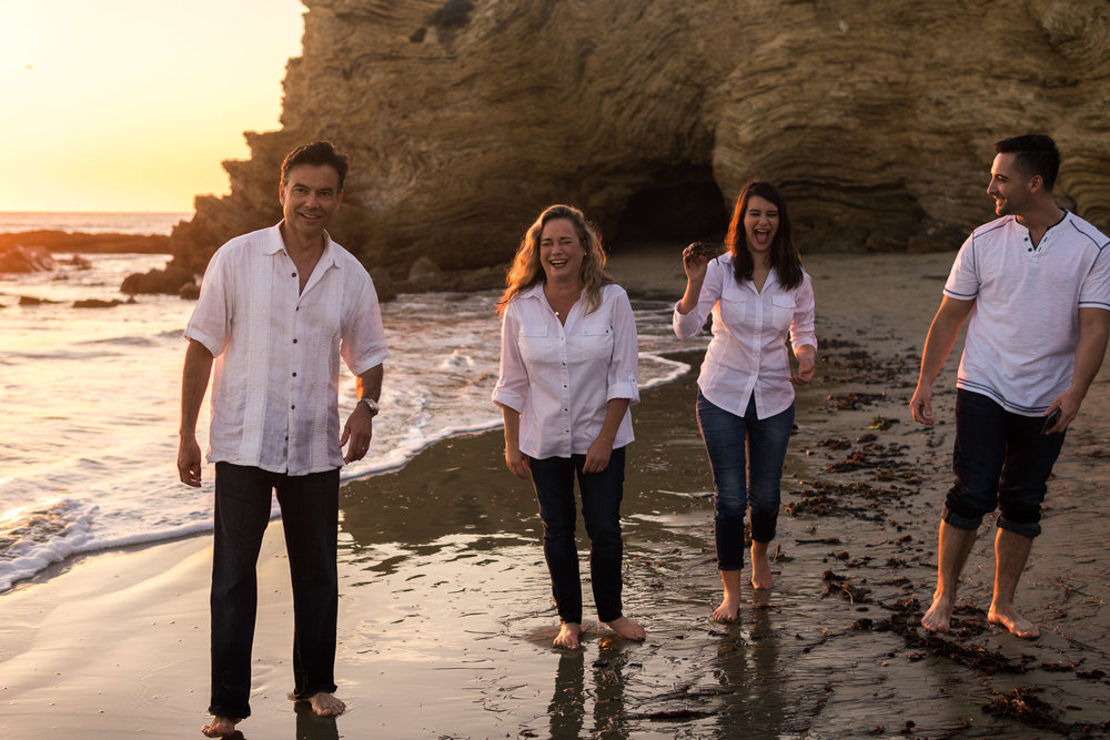 Family portraits of family walking on the beach laughing during Golden hour at Crystal Cove State Beach in Newport