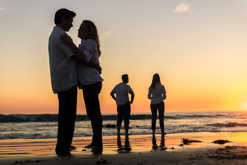 Family portraits of family silhouettes with a  glassy seashore while enjoying the sunset together during Golden hour at Crystal Cove State Beach in Newport