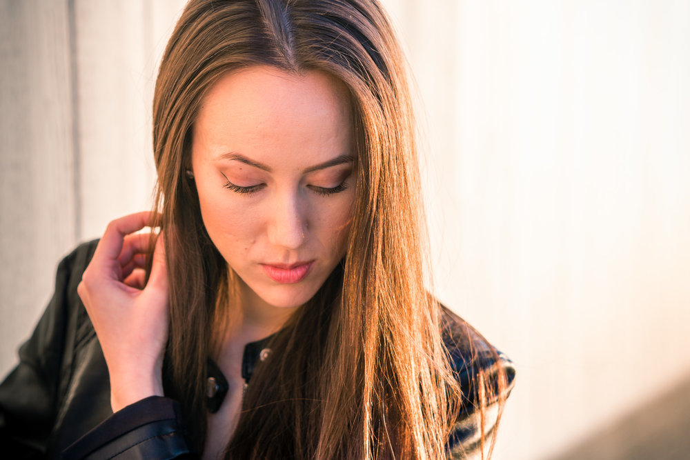 Natural light Fashion Portrait of female model wearing black leather jacket and blue jeans taken during Golden hour At Balboa Pier in Newport Beach