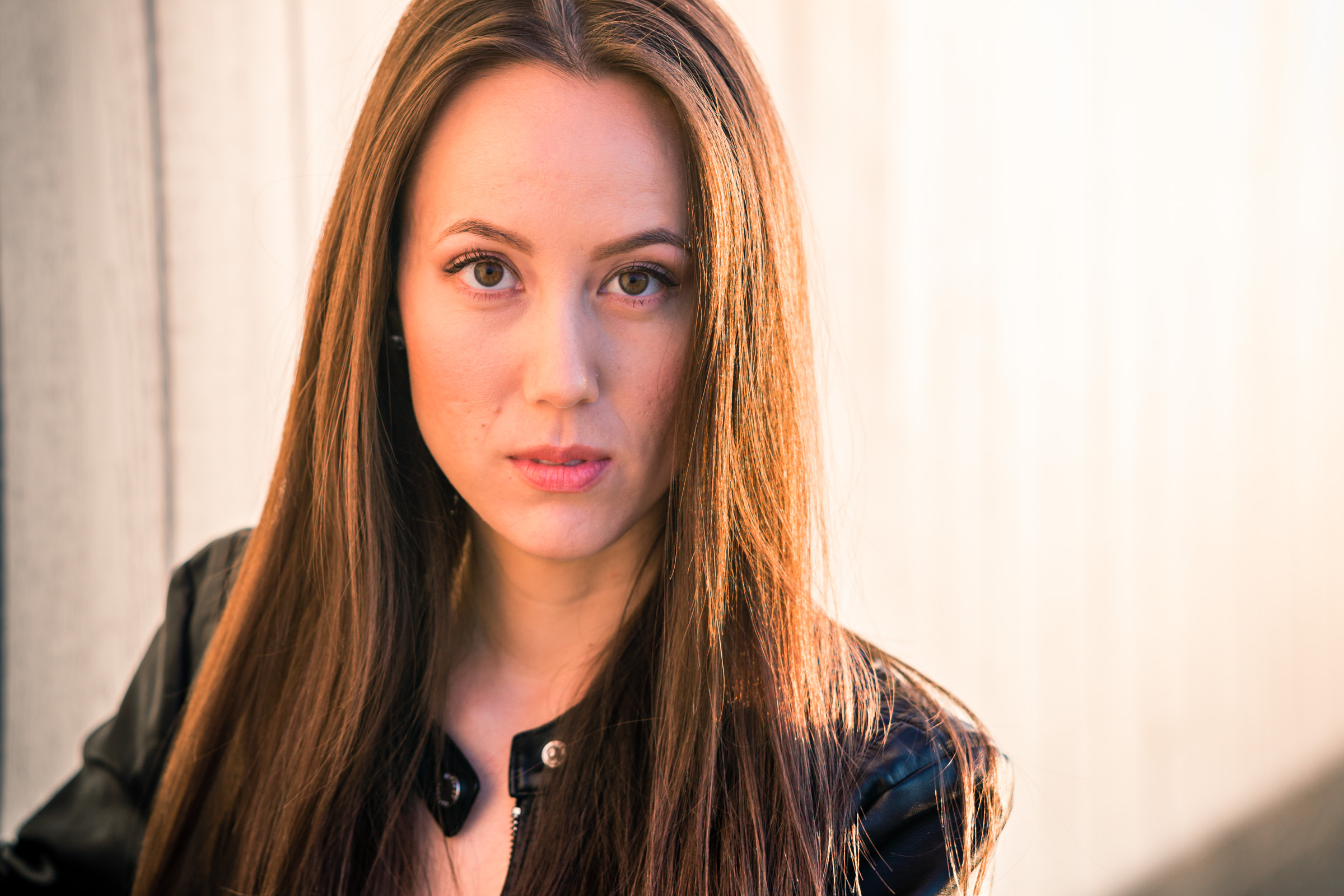 Natural light Fashion Portrait of female model wearing black leather jacket and blue jeans taken during Golden hour At Balboa Pier in Newport Beach