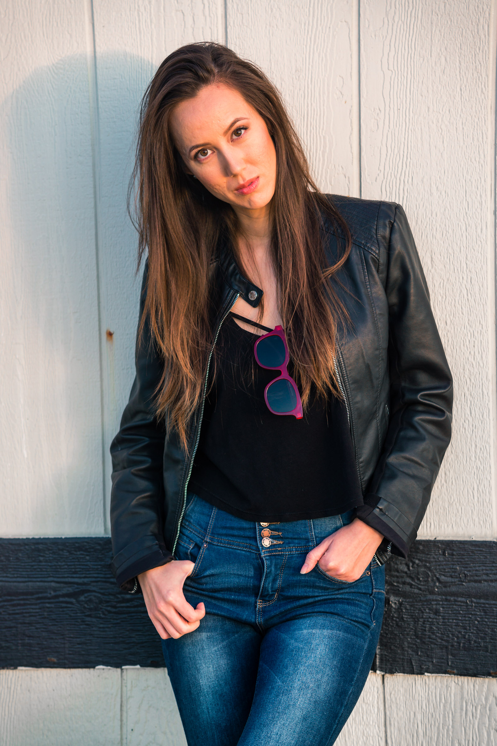 Natural light Fashion Portrait of female model wearing black leather jacket and blue jeans taken during Golden hour At Balboa Pier in Newport Beach