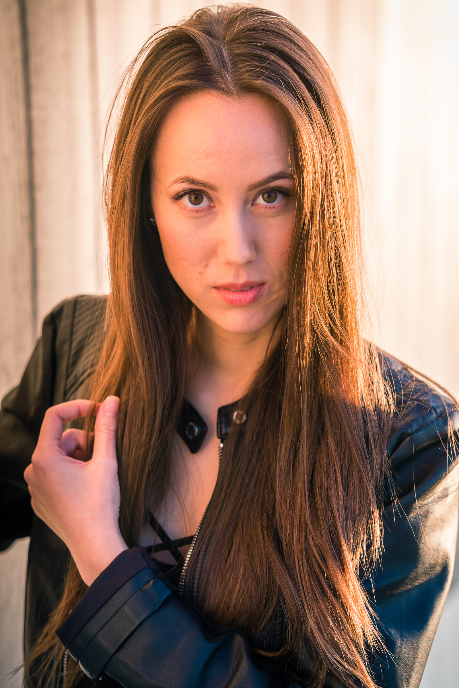 Natural light Fashion Portrait of female model wearing black leather jacket and blue jeans taken during Golden hour At Balboa Pier in Newport Beach