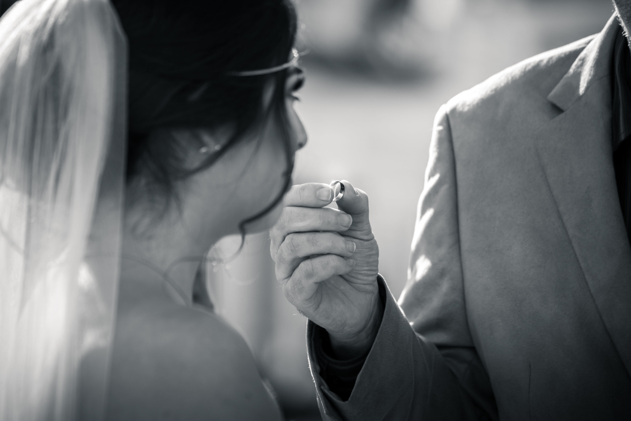 Black-and-white photo  of The pastor handing the wedding ring to The bride at the altar
