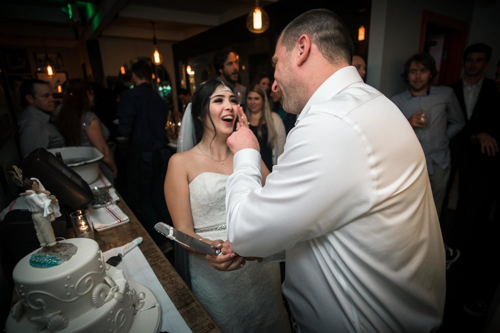 The groom smearing wedding cake on the brides face