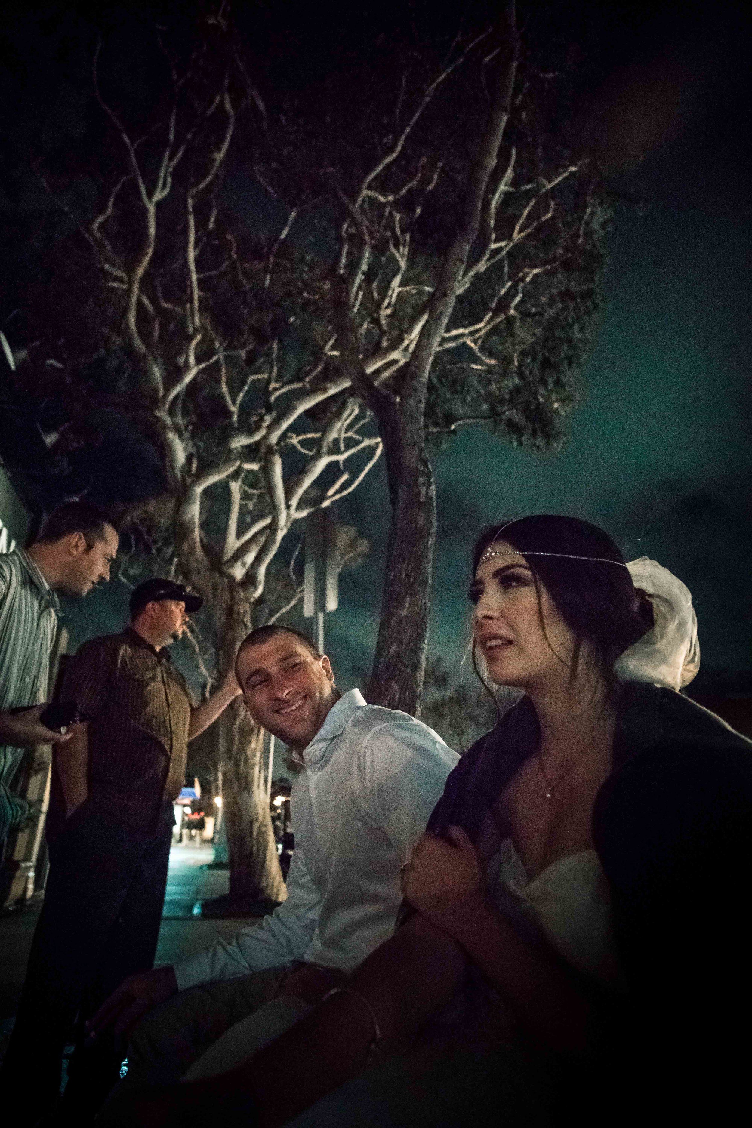 Bride and groom and wedding guests sitting outside at night after the Reception