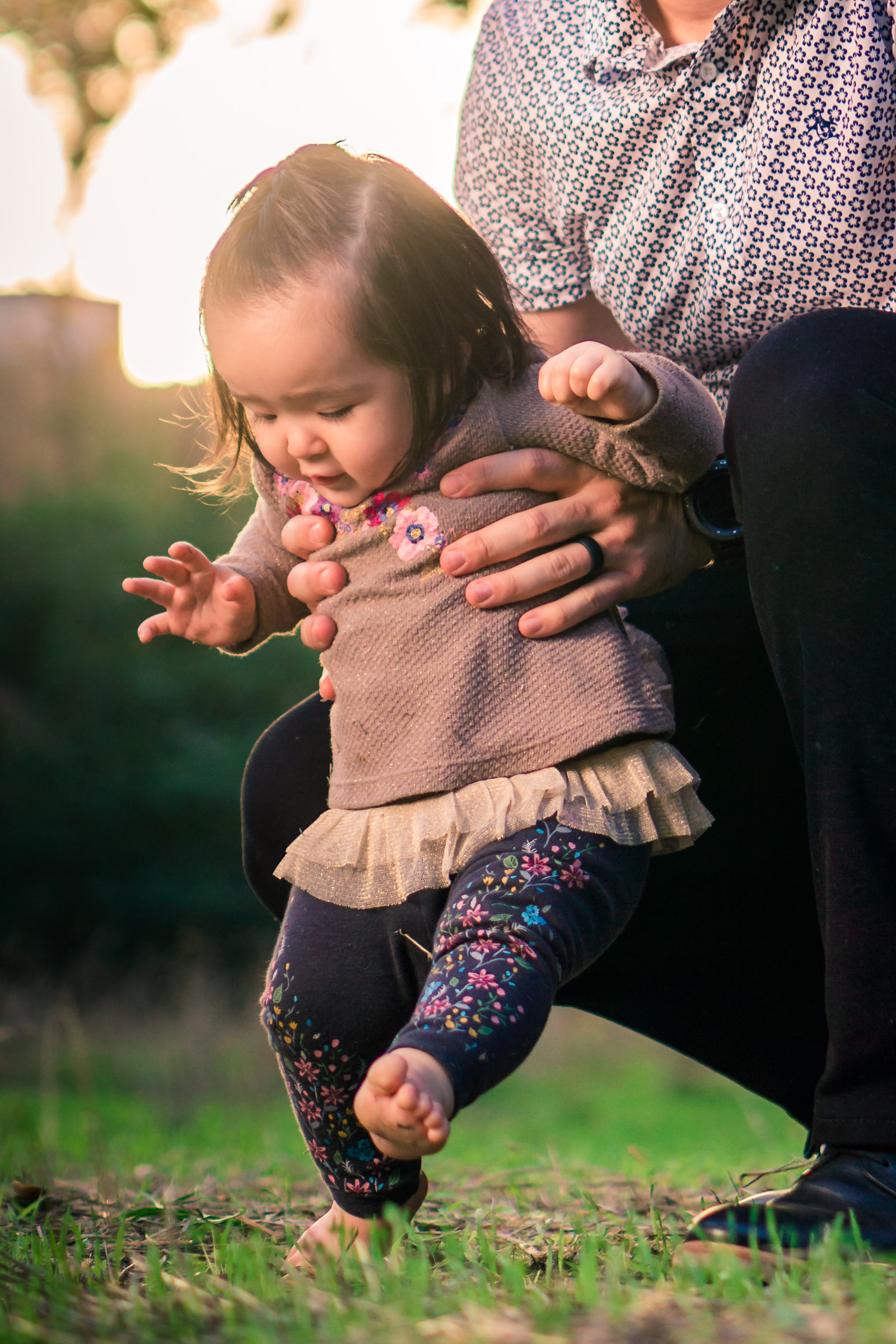 Portrait of a cute Little baby girl  learning to walk in the grass on the Juanita Cooke Trail in Fullerton during a family portrait session