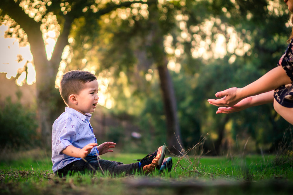 Portrait of a cute little boy crying with mother helping him during a family portrait session in fullerton orange county taken by joseph barber photography