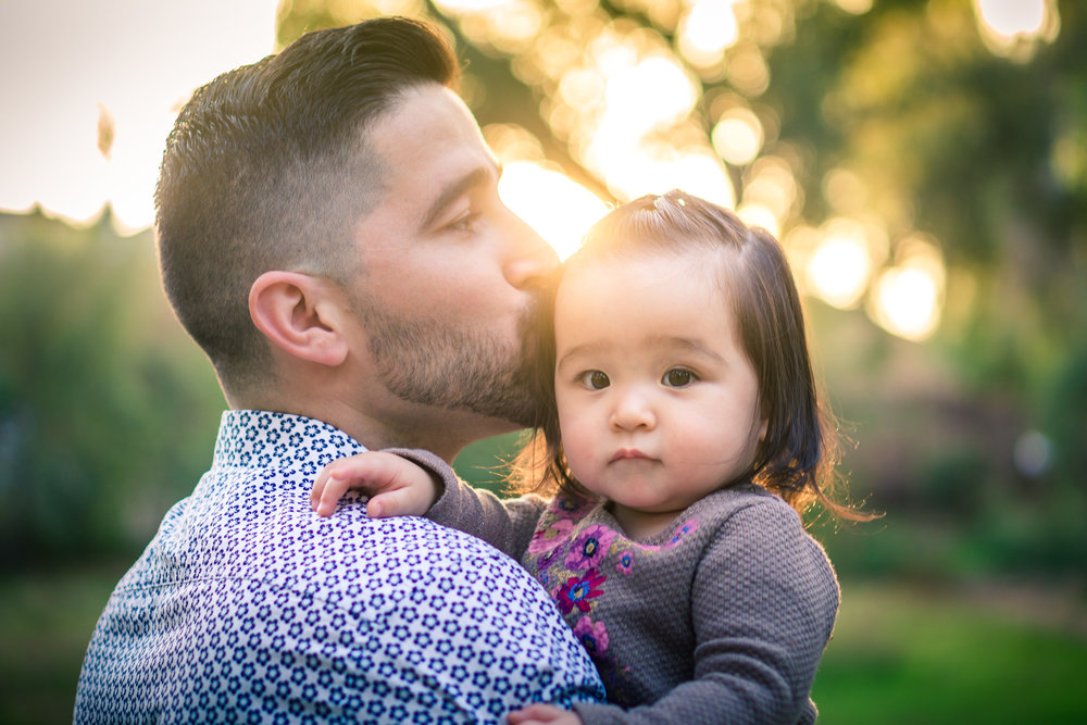 Portrait of a father kissing his cute little baby girl during a family portrait session in fullerton orange county taken by joseph barber photography