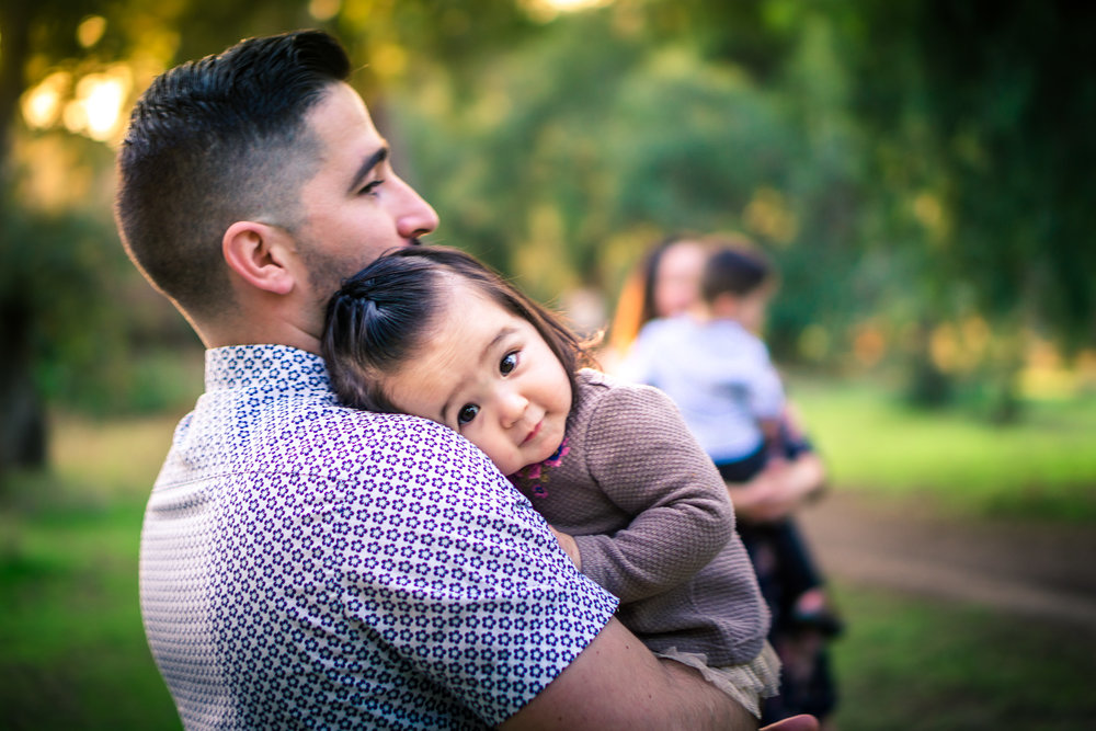 Portrait of a father holding his cute little baby girl on his shoulder during a family portrait session in fullerton orange county taken by joseph barber photography