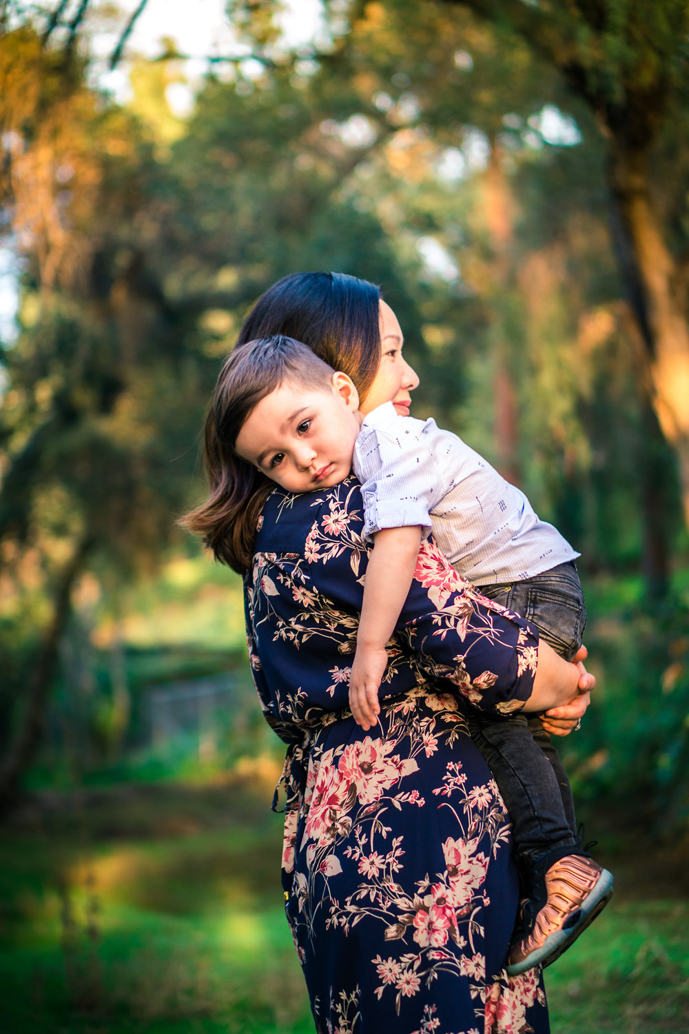 candid photo of a mother holding tired little boy on his shoulder during a family portrait session  on the juanita cooke trail in fullerton orange county taken by joseph barber photography