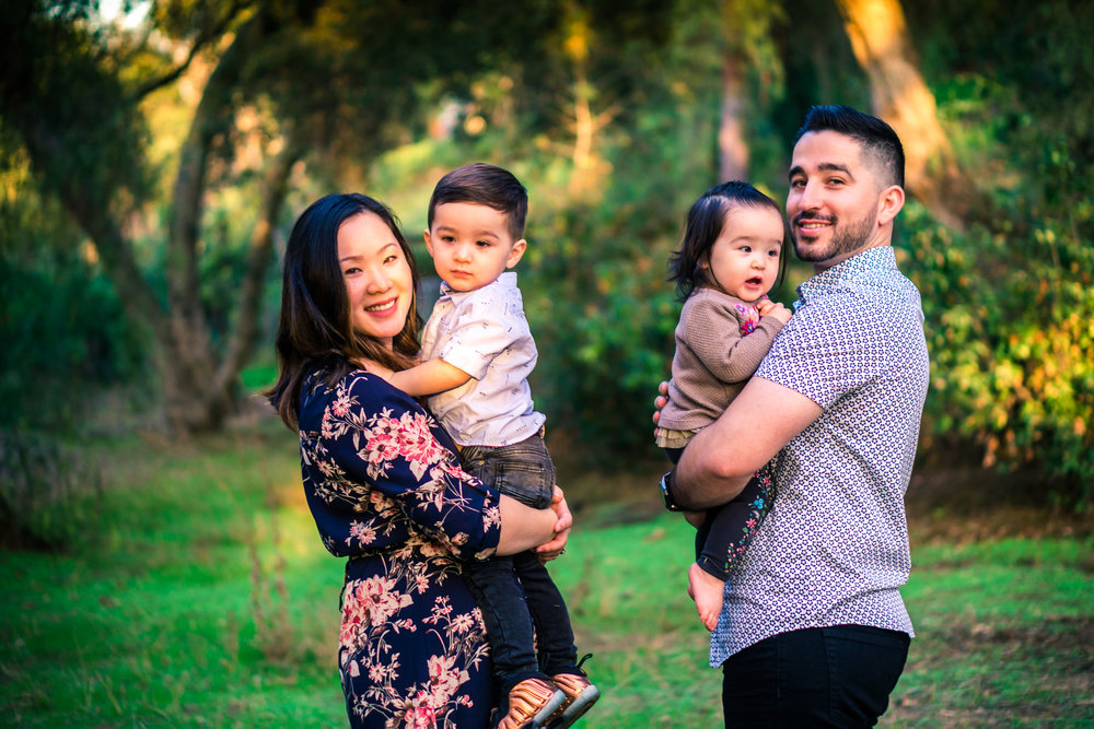 photo of a mother and father holding their little children during a family portrait session  on the juanita cooke trail in fullerton orange county taken by joseph barber photography