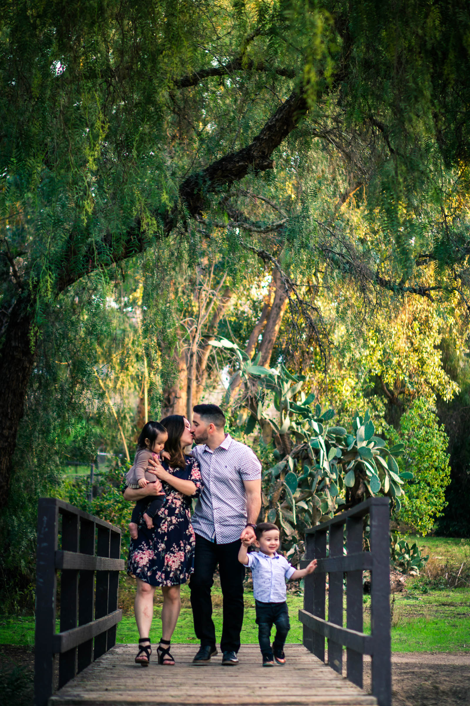 photo of a family walking across a bridge through a park during a family portrait session  on the juanita cooke trail in fullerton orange county taken by joseph barber photography