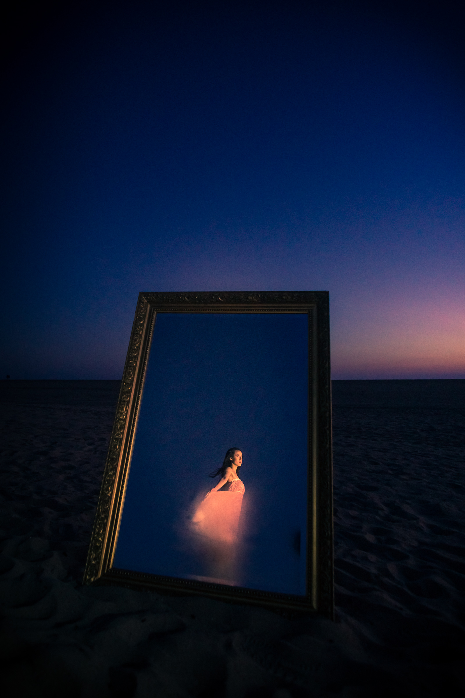 Experimental portrait with a vintage mirror with a lady a in a pink dress taken on the beach on Balboa Peninsula