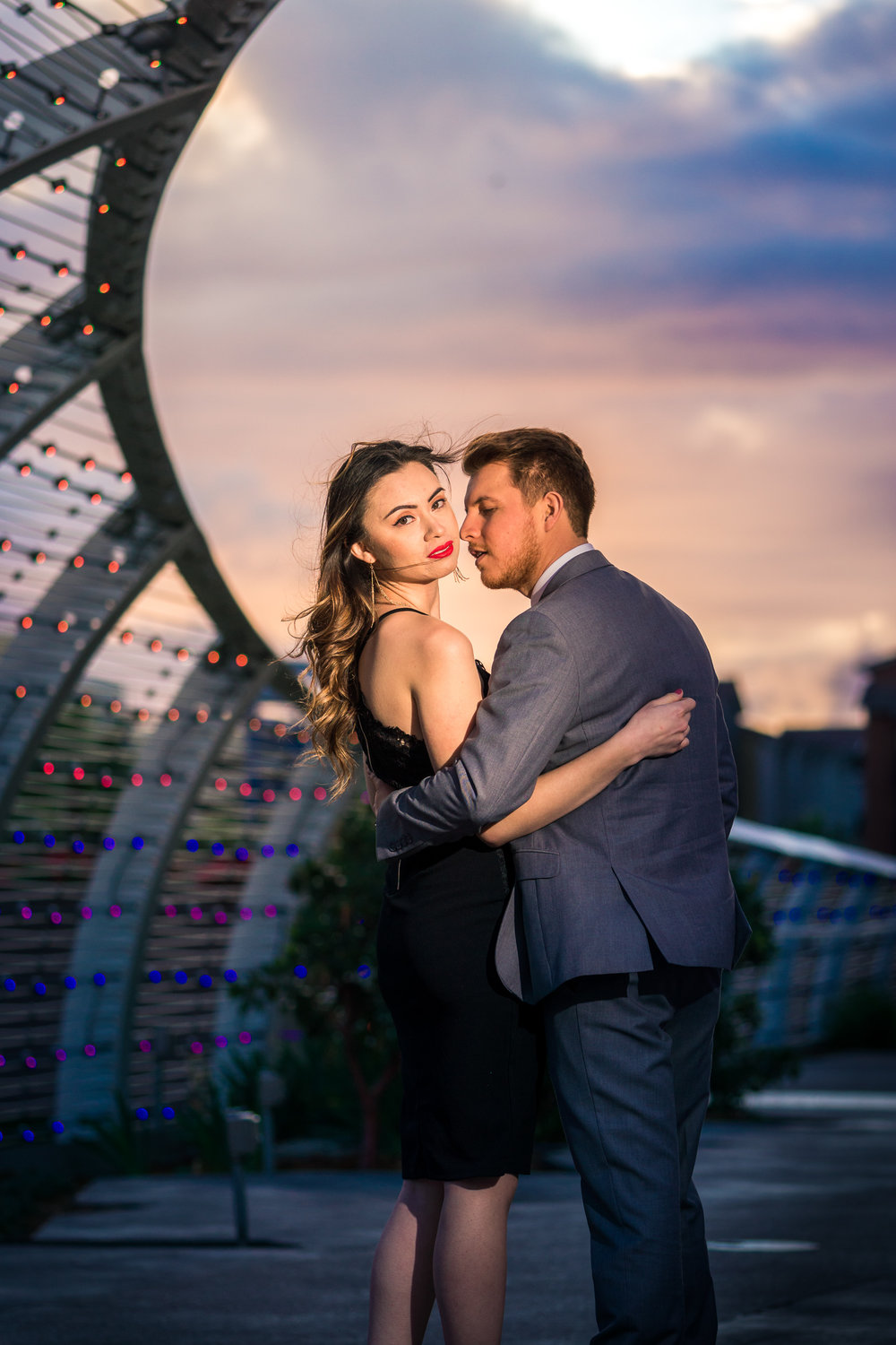 Professional portrait taking a golden hour Of a beautiful Couple Under the rainbow bridge at the Long Beach convention Center