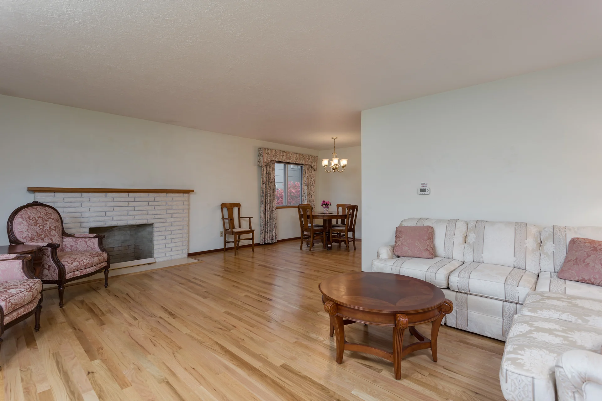 Spacious living and dining area with hardwood floors and cozy fireplace.